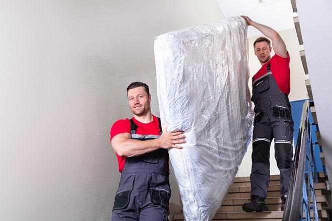 team of workers maneuvering a box spring through a doorway in Streamwood